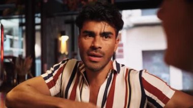 Bira barında kutlama yapan üç çok ırklı arkadaş. Genç İspanyol adam arkadaşlarıyla konuşuyor. Yakın çekim.