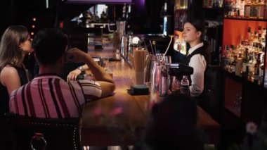 Genç bayan barmen, bira barında kutlama yapan üç çok ırklı arkadaşla konuşuyor. Orta boy.