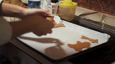 Anne ve kızı Noel için zencefilli kurabiye yapıyor. Genç bir kadın, yıldız şeklindeki hamuru pişirme tepsisine koyar..