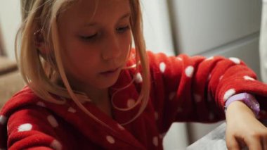 Anne ve kızı Noel için zencefilli kurabiye yapıyor. Kırmızı noktalı pijamalı çocuk hamuru fırın kağıdıyla kaplı bir tepsiye koyar. Yakın plan.