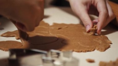 Anne ve kızı Noel için zencefilli kurabiye yapıyor. Kırmızı pijamalı çocuk, pişirme kağıdıyla kaplı bir tepside kum hamuru figürleri şekillendiriyor. Yakın plan.