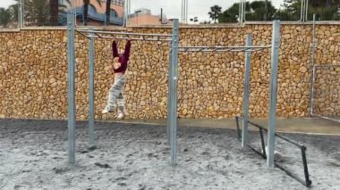 Noel kıyafeti giyen genç bir kız oyun parkında maymuna ters hareket ederken eğleniyor. Geniş açı