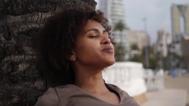 Yoga yapan genç bir kadın sakin bir sabah oturumunda palmiye ağacının yanında poz veriyor, arkada ikonik Benidorm Intempo gökdeleni var. Yakın plan.