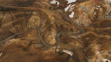 Karlı yamaçları, kıvrımlı dereleri ve buhar bacaları olan paslı tepeler Kerlingarfjoll, İzlanda 'daki jeotermal aktiviteyi vurguluyor..