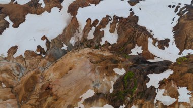 Landmannalaugar, İzlanda 'daki Rhyolite dağları, engebeli arazide canlı turuncu, kahverengi ve bej renkli karlar ve yeşil yosunlar sergiler..