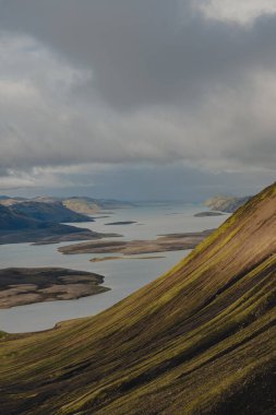 Yuvarlanan tepeler, çimenli yamaçlar ve bulutlu gökyüzünün altındaki küçük adalarla çevrili sakin bir su kütlesi İzlanda 'nın engebeli arazisini gözler önüne seriyor..