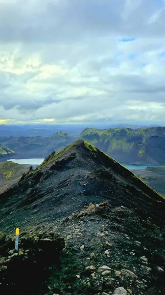 İzlanda 'daki engebeli volkanik dağ yosunları vadide dingin bir göl, uzak dağlar ve kasvetli bir atmosfer yaratan bulutlu bir gökyüzü..