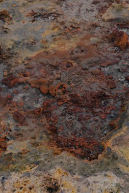 İzlanda 'da paslı mineral yatakları, sarı ve gri yamalar ve jeotermal aktiviteden düz olmayan dokuların yer aldığı jeotermal bir yüzeye yakından bakın..