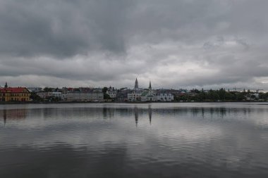 Reykjavik, İzlanda manzarası, Tjornin göleti, Hallgrimskirkja kulesi, Frikirkjan kilisesi ve bulutlu gökyüzü altında renkli geleneksel mimari.