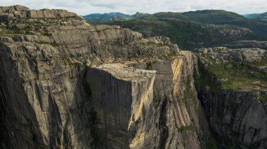 Norveç 'te düz bir uçurum olan Preikestolen, Lysefjord üzerinde sarp kayalıklar, engebeli arazi, yeşillik ve uzak dağlarla çevrili..