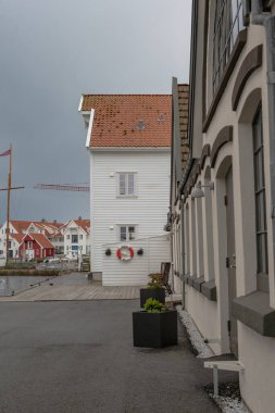 Norveç 'te kırmızı ve beyaz cepheli geleneksel İskandinav tarzı binalar. Yakınlarda tahta bir yelkenli direği ve vinç görünüyor..