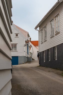 Norveç 'in sakin bir sahil köyünde kırmızı ve turuncu kiremitli çatıları olan beyaz ahşap evlerle dolu sessiz, eğimli bir cadde..