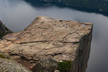 Norveç 'te düz bir uçurum olan Preikestolen, Lysefjord' un üzerinde yükseliyor. Sahnede engebeli kaya oluşumları, sakin sular ve yemyeşil alanlar yer alıyor..