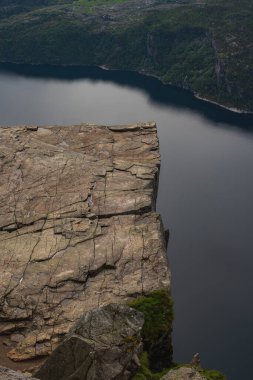 Norveç 'te düz bir uçurum olan Preikestolen, engebeli arazi ve yeşil tepelerle çevrili Lysefjord' un sakin sularının üzerinde yükselir..