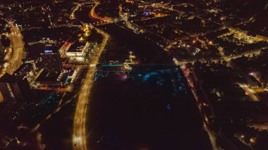 Vilnius, Litvanya 'nın gece hava manzarası, aydınlatılmış Neris Nehri, Radisson Blu Oteli, aydınlık yollar ve kentsel işaretler.