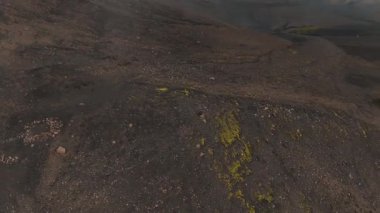 Yoğun siste yükselen bir dron, İzlanda 'nın engebeli volkanik manzarasını ortaya çıkarıyor. Kar parçaları ve küçük bir yansıtıcı su kütlesi..