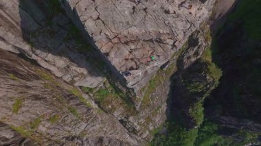 İnsansız hava aracı Lysebotn yakınlarındaki bir kanyonda hareket ederek kaya oluşumlarını, yemyeşil alanları, dar bir su yolunu ve görünür ölçekte düz bir kaya yüzeyini ortaya çıkarıyor..