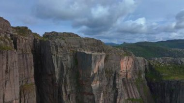 İnsansız hava aracı Lysebotn yakınlarındaki bir kanyonu süpürüyor, sarp kayalıkları, karmaşık kaya dokularını, küçük gölleri ve hareket halindeki yeşillikleri gösteriyor..