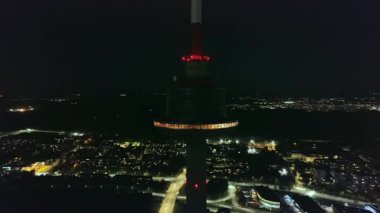 Litvanya 'daki Vilnius TV Kulesi' nin gece görüşü. Parlayan gözlem güvertesi ışıkları, yanıp sönen kırmızı havacılık ışıkları ve hareket eden kamera perspektifi..