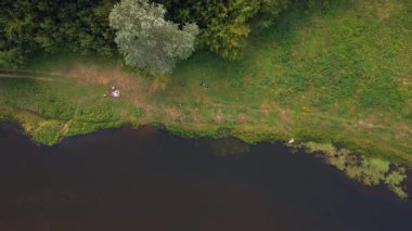 Polonya 'nın Nowy Lubiel şehrinde yeşil ve ormanla çevrili sakin bir nehrin havadan görünüşü. Nehir boyunca uzanan pis bir patika görünür bir eğlence aktivitesi içeriyor..