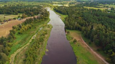 Polonya 'nın Nowy Lubiel kentinden akan bir nehrin havadan görünüşü. Etrafı ormanlarla, tarlalarla ve dağılmış binalarla çevrili..