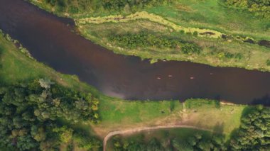 Polonya 'nın Nowy Lubiel kentindeki bir nehrin hava perspektifi, yoğun bitki örtüsü ve açık alanlarla çevrili, akıntı yönünde hareket eden kanolarla..