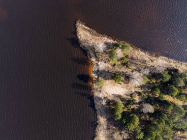 Berezivka ya da Minsk, Belarus yakınlarındaki koyu sularla çevrili yeşil kozalaklı ağaçlar ve çıplak yamalarla çevrili dar bir yarımadanın havadan görünüşü.
