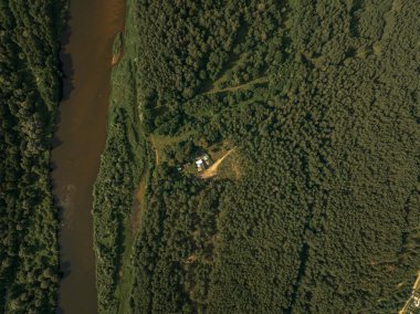 Solunda kıvrımlı kahverengi bir nehir olan yoğun bir orman, merkezinde binalar bulunan küçük bir açıklık, Beyaz Rusya 'nın Berezivka kentinin yukarısından ele geçirildi..