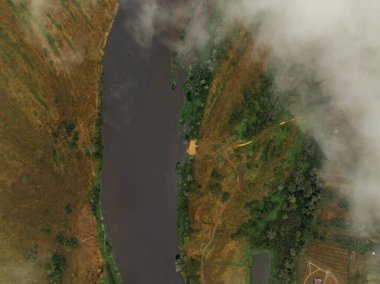 Nehir, sağ kıyıda yoğun yeşillik ve sol tarafta kısmen sisle kaplanmış açık çimenli arazi ile karışık bitki örtüsünün içinden akar..