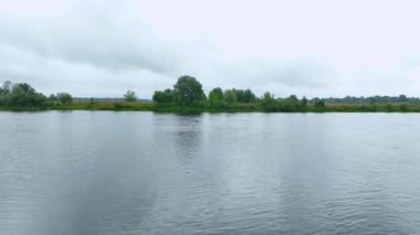 Beyaz Rusya 'da ağaçların ve çalıların olduğu düz bir arazinin havadan görünüşü. İnsansız hava aracı gri bulutlarla bulutlu bir gökyüzünün altında ilerler..
