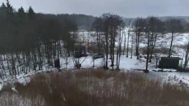 Litvanya 'daki donmuş bir gölün havadan görünüşü yoğun ormanlar, sazlıklar ve bulutlu bir gökyüzünün altındaki küçük ağaçlarla çevrili..