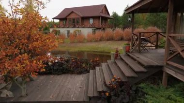 Sonbaharda yeşil, sarı ve turuncu yapraklı bir Litvanya ormanı manzarası. Kamera yukarı doğru hareket ederken kırmızı kiremitli çatı görülebilir..