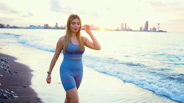 Красивая Молодая Женщина Спортивной Одежде Прогулки Вдоль Пляжа Закате Фоне — стоковое видео