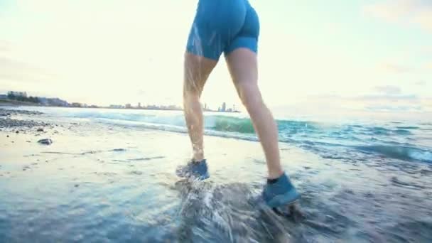 Спортивные Женщины Бегают Пляжу Ноги Видны Неузнаваемы Брызги Воды Волн — стоковое видео
