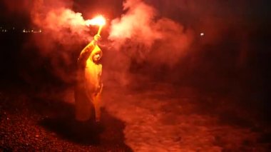 a lone person traveler in yellow wind protection gives a signal fire at night