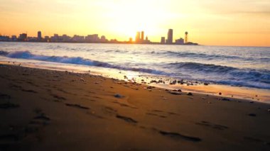 a beautiful seascape at sunset against the background of a modern urban landscape silhouettes of skyscrapers