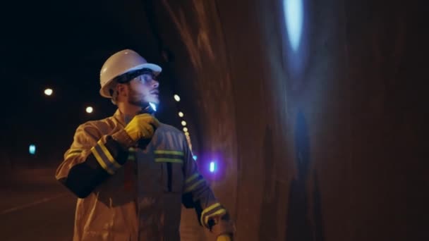 白い硬い帽子の労働者が地下のトンネルを調べて壁を調べ — ストック動画