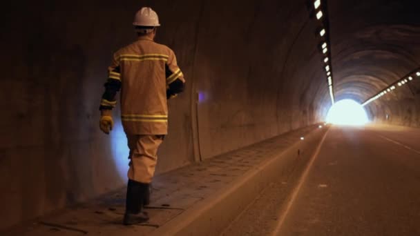 道路局の職員又はヘルメットの技術者で懐中電灯を手に車のトンネルの壁を検査するもの — ストック動画