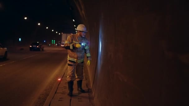 头戴头盔 身穿制服的男子手持手电筒检查行车隧道 — 图库视频影像