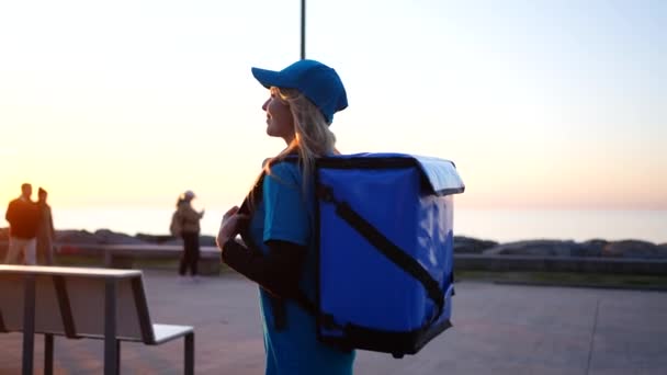 一个年轻的女人是带着背包 信使或运送货物或购买物品给客户的送货员 — 图库视频影像