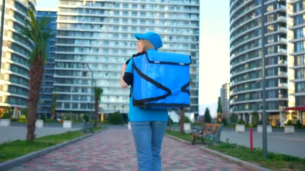 一个年轻的女人是带着背包 信使或运送货物或购买物品给客户的送货员 — 图库视频影像