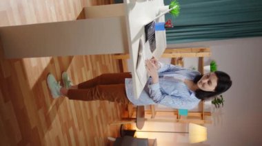 Kadın bir serbest çalışan oturma odasında masa başında çalışıyor.