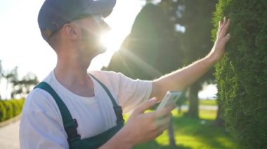 Erkek bahçıvan akıllı telefon elinde internet araması elinde fabrikayı kontrol ediyor