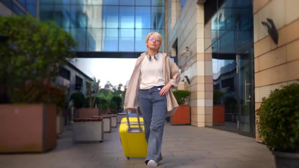 スーツケースを着た若い女性が通りを短い髪で歩き — ストック動画