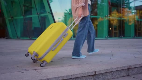 現代の空港ビルを背景に黄色のスーツケースのクローズアップ認識できない男の旅行者カジュアル服 — ストック動画