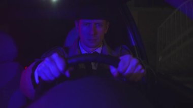 Sinema, arabanın direksiyonunun arkasındaki kameraya bakan, retro tarzı ciddi bir adamın portresini çekti.