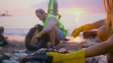 Gün batımında plastikten sahili temizleyen gönüllülerden oluşan pozitif bir ekip.