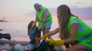 Gün batımında plastikten sahili temizleyen gönüllülerden oluşan pozitif bir ekip.