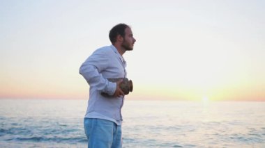 Bir seremoni. Bir adam elleriyle denizin arka planına kül atar.