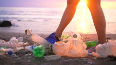 Gönüllü, plastikle kirlenmiş deniz kıyısı boyunca yürüyor. Çevresel bir sorun.